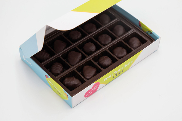 Caja de bombones con bandeja termoformada y tapa semidesplegada, packaging de cartón con diseño colorido pensado para líneas de producción a gran escala