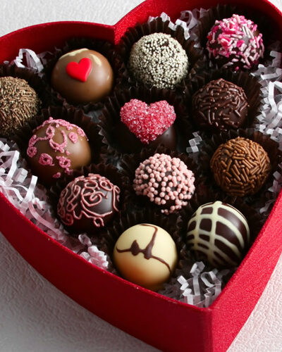 Caja de bombones con forma de corazón, rellena de trufas decoradas artesanalmente, ideal como packaging para San Valentín o regalos románticos